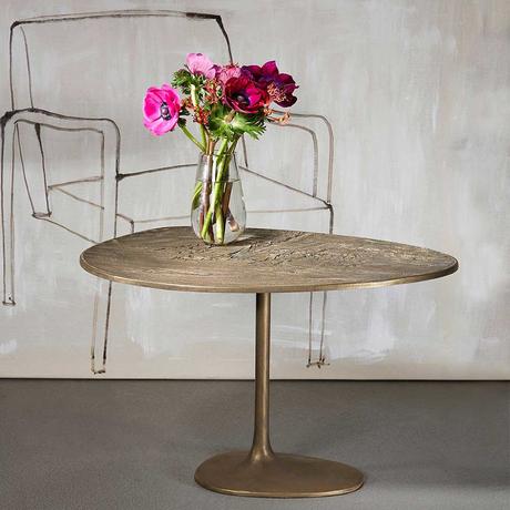 Table basse contemporaine avec un bouquet de fleur dans un vase posé sur la table, un dessin de fauteuil sur le mur