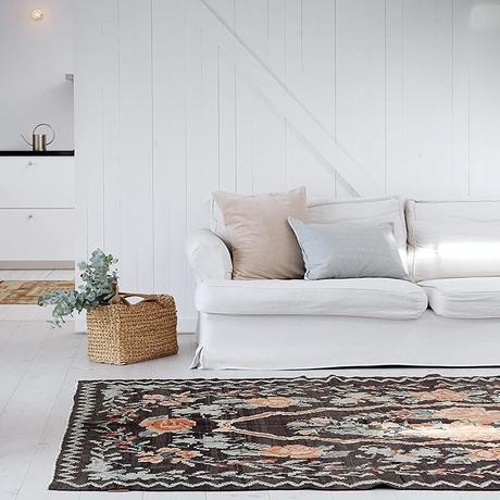 salon maison vacances déco blanche canapé lin tapis kilim motif floral noir